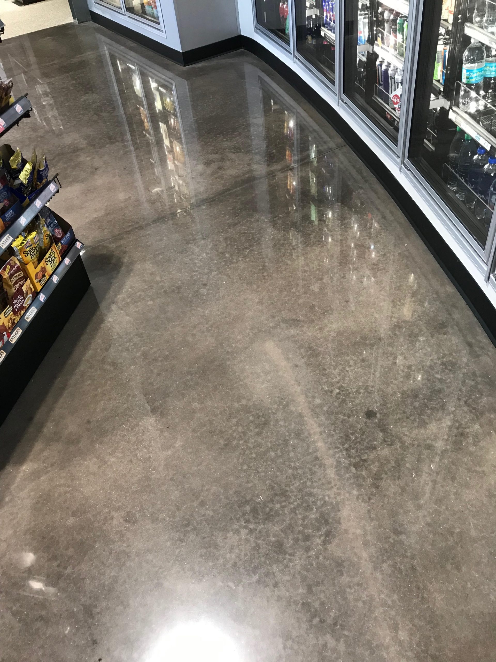 Polished concrete floor with a reflective finish beside refrigerated displays in a retail store