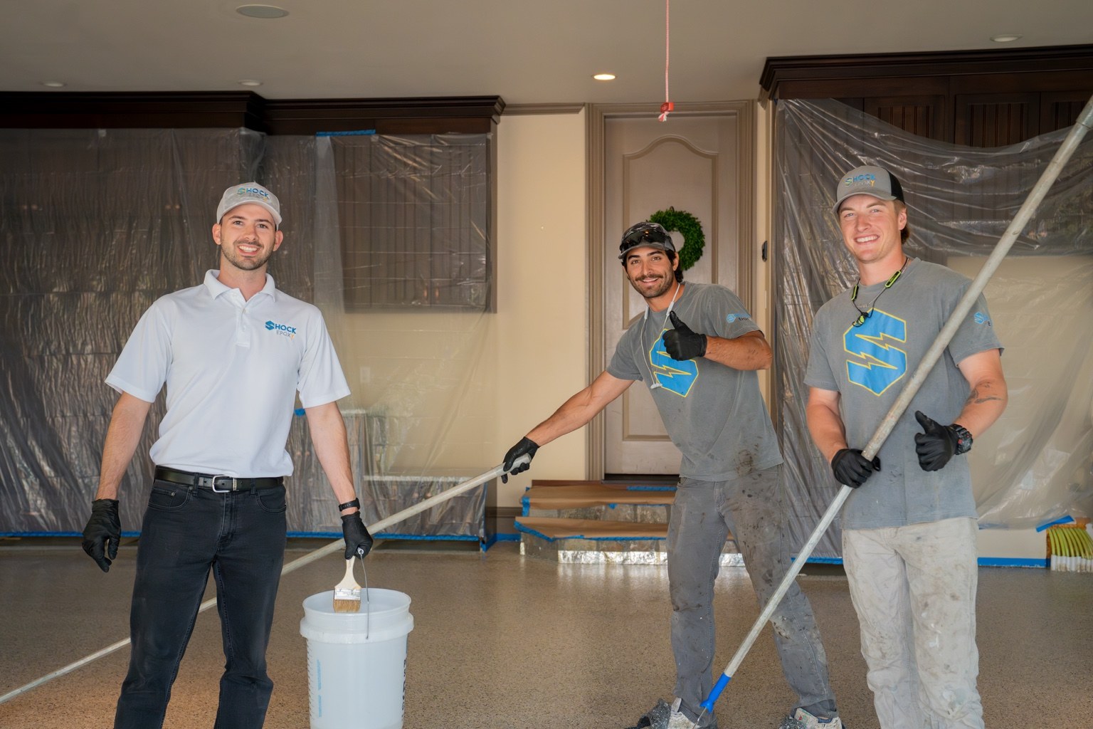 Shock Epoxy owners on a flooring project: Davis on the left, Jack in the middle toward the back, and Aidan on the front right
